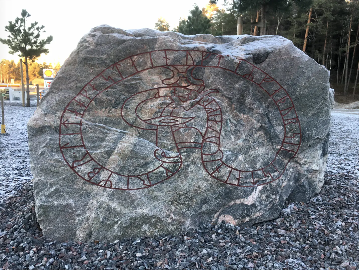 Grov grå sten med röd runorm som slingrar sig i en stor åtta över ytan.